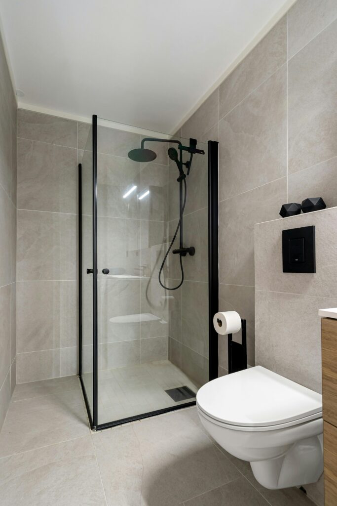 Baño minimalista reformado con mampara negra y ducha moderna